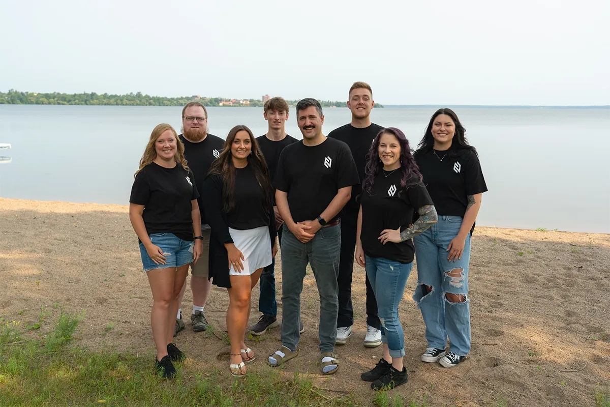 Group of people by a lake, smiling.