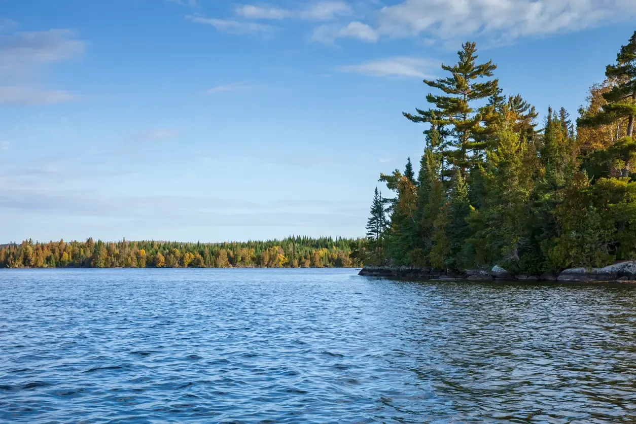 Scenic lake with trees and blue sky.
