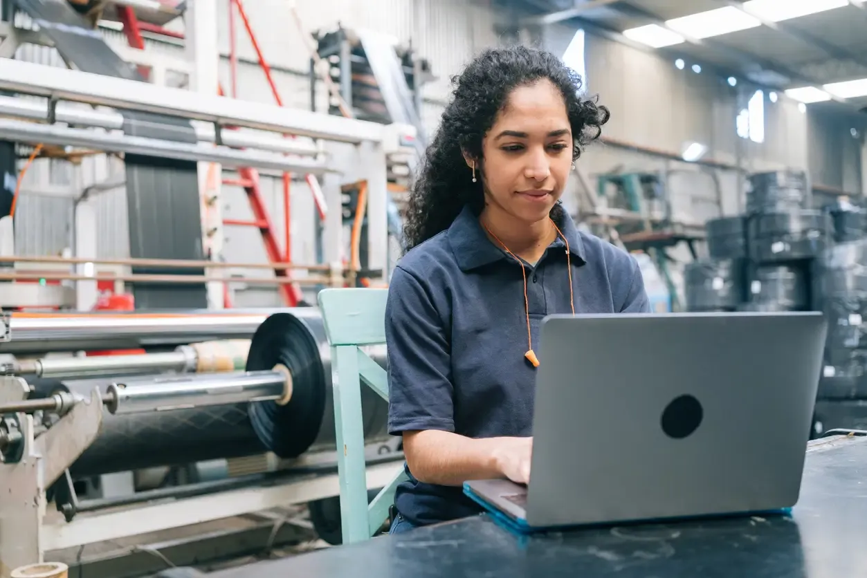 woman on laptop in a manufacturing facility